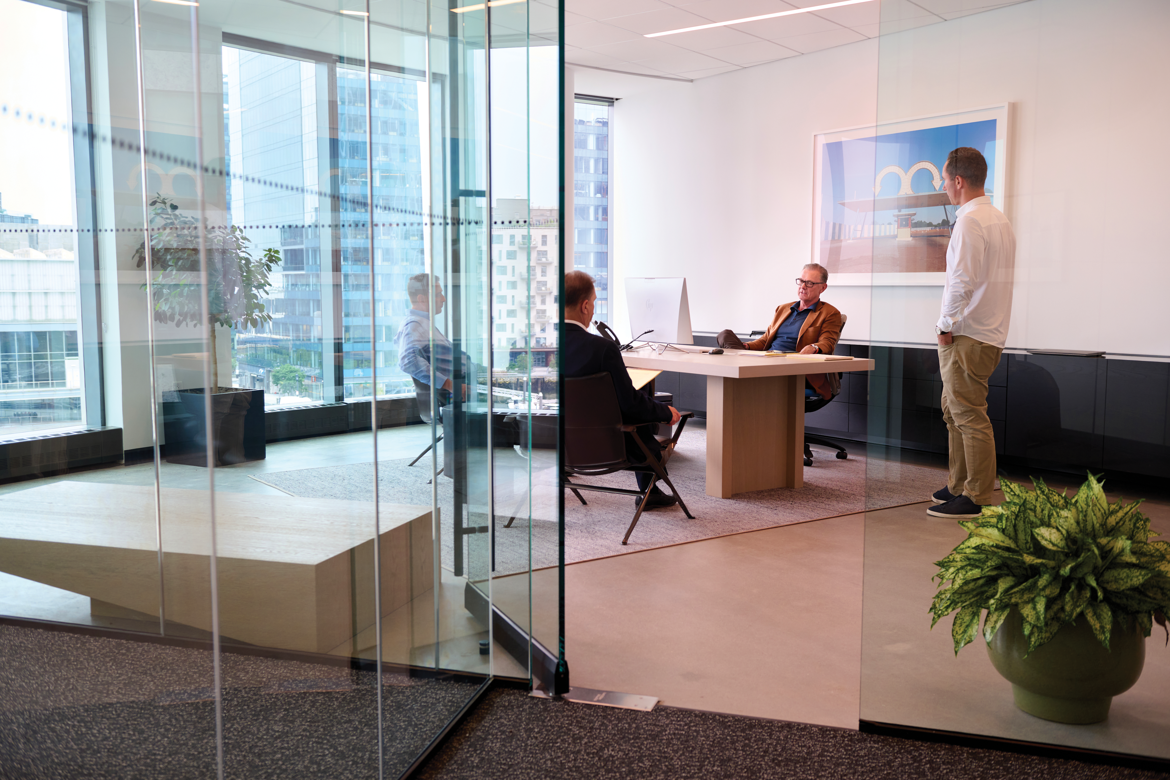A handful of executives meet in a glass conference room in a high-rise office building