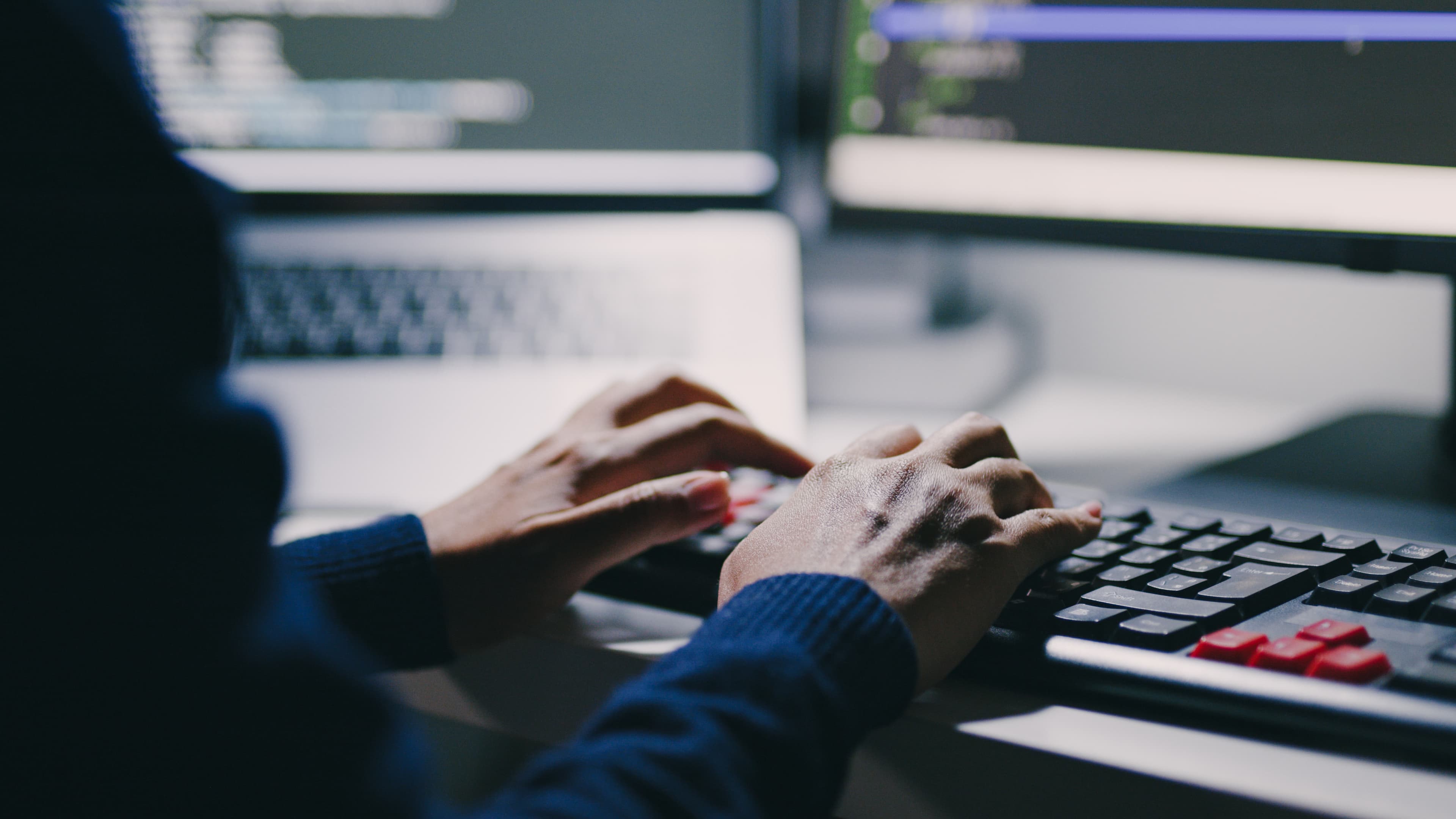 Two hands typing on a keyboard