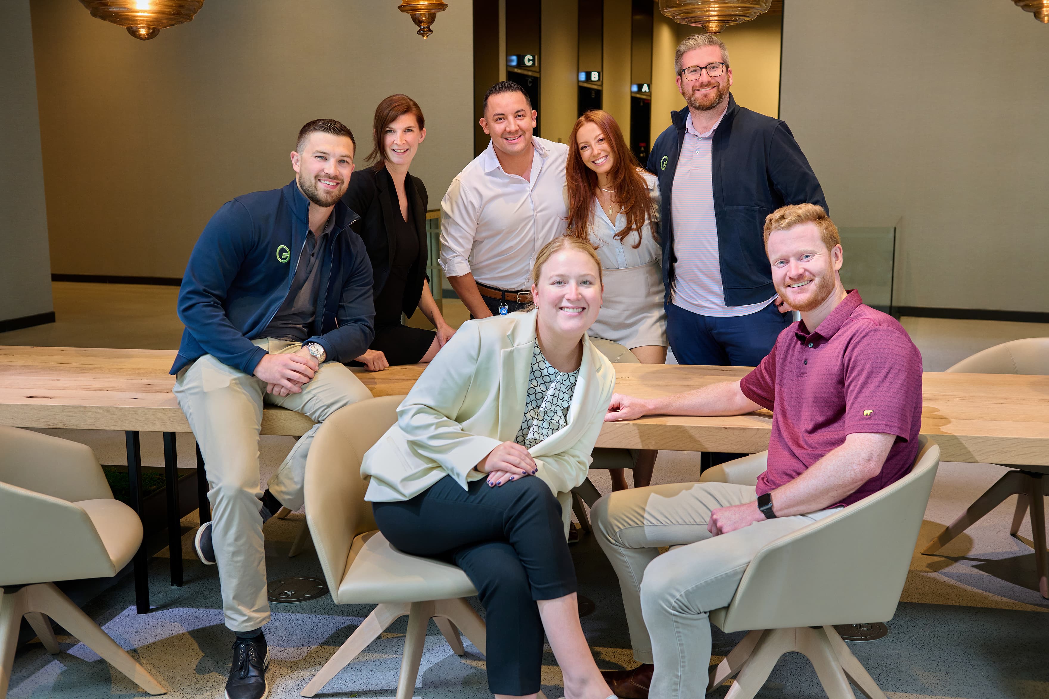 Group of Fusion Worldwide employees sitting around a table, smiling at the camera