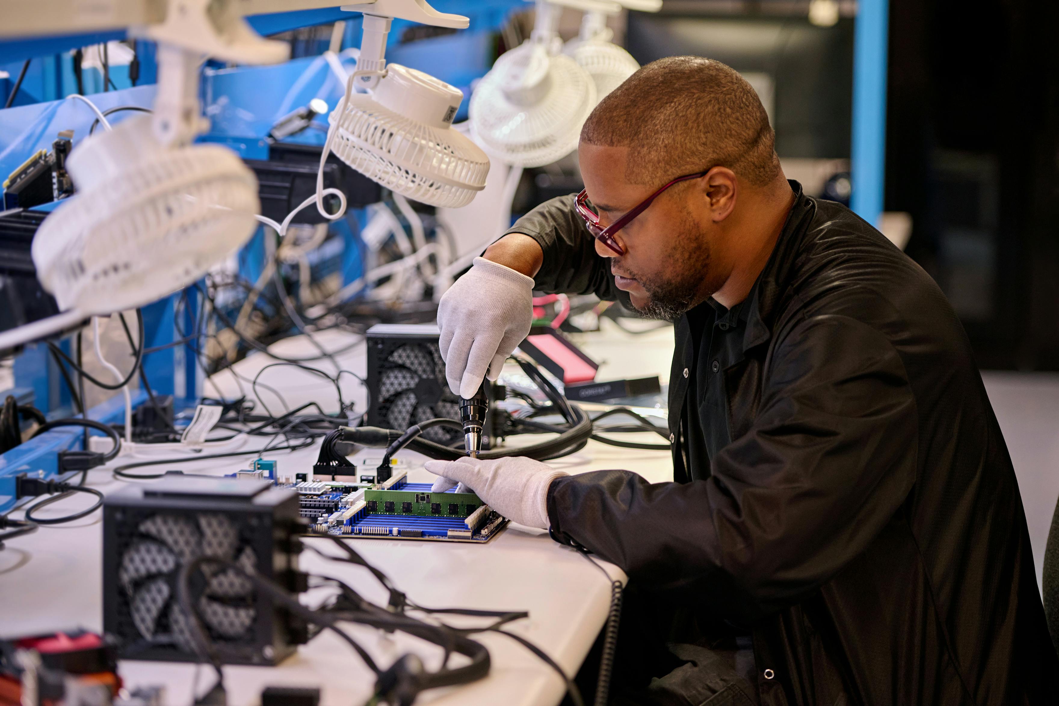 An employee performs a functional test of electronic components while wearing protective gloves