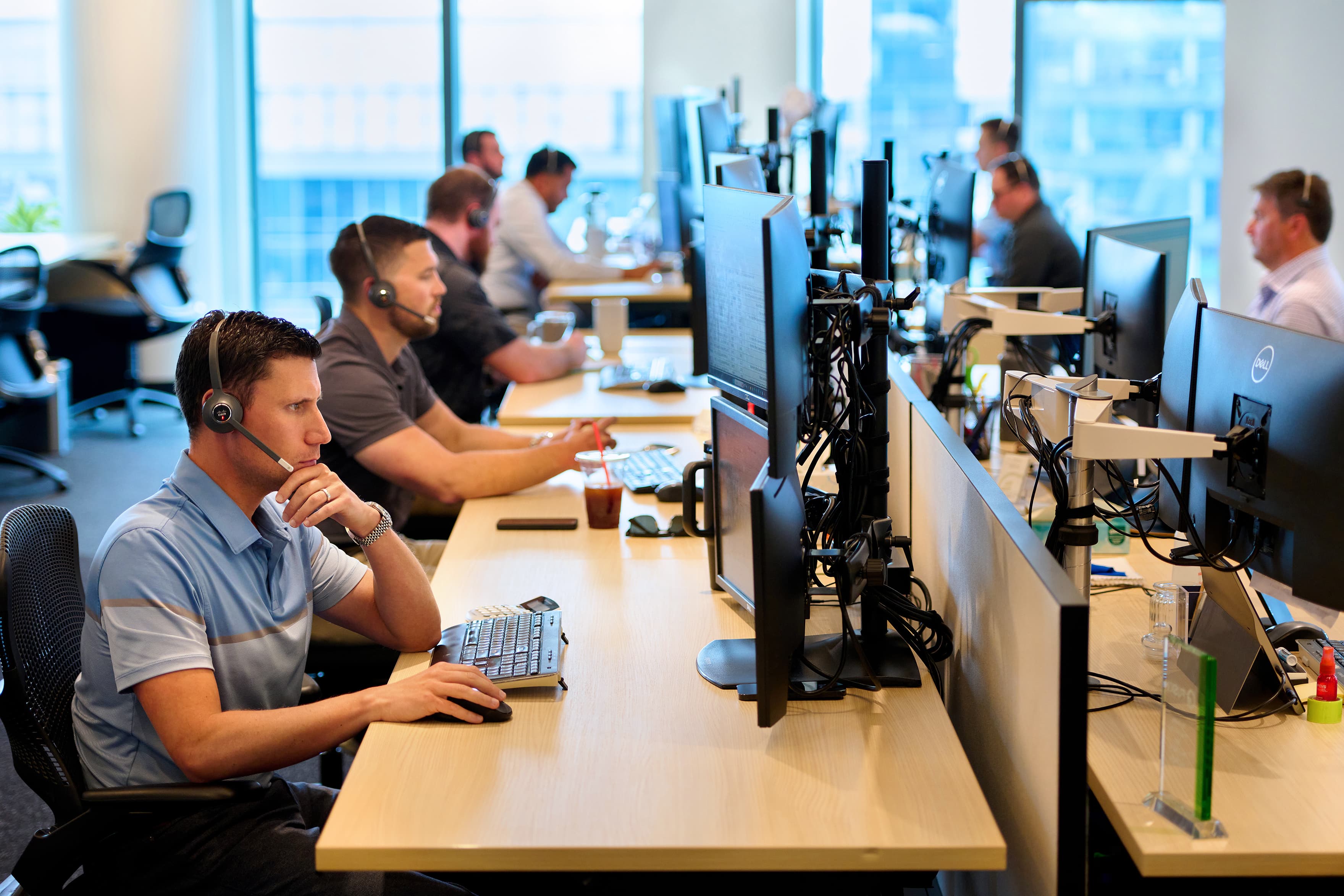 Open office plan sales floor with employees in headsets working at their desks