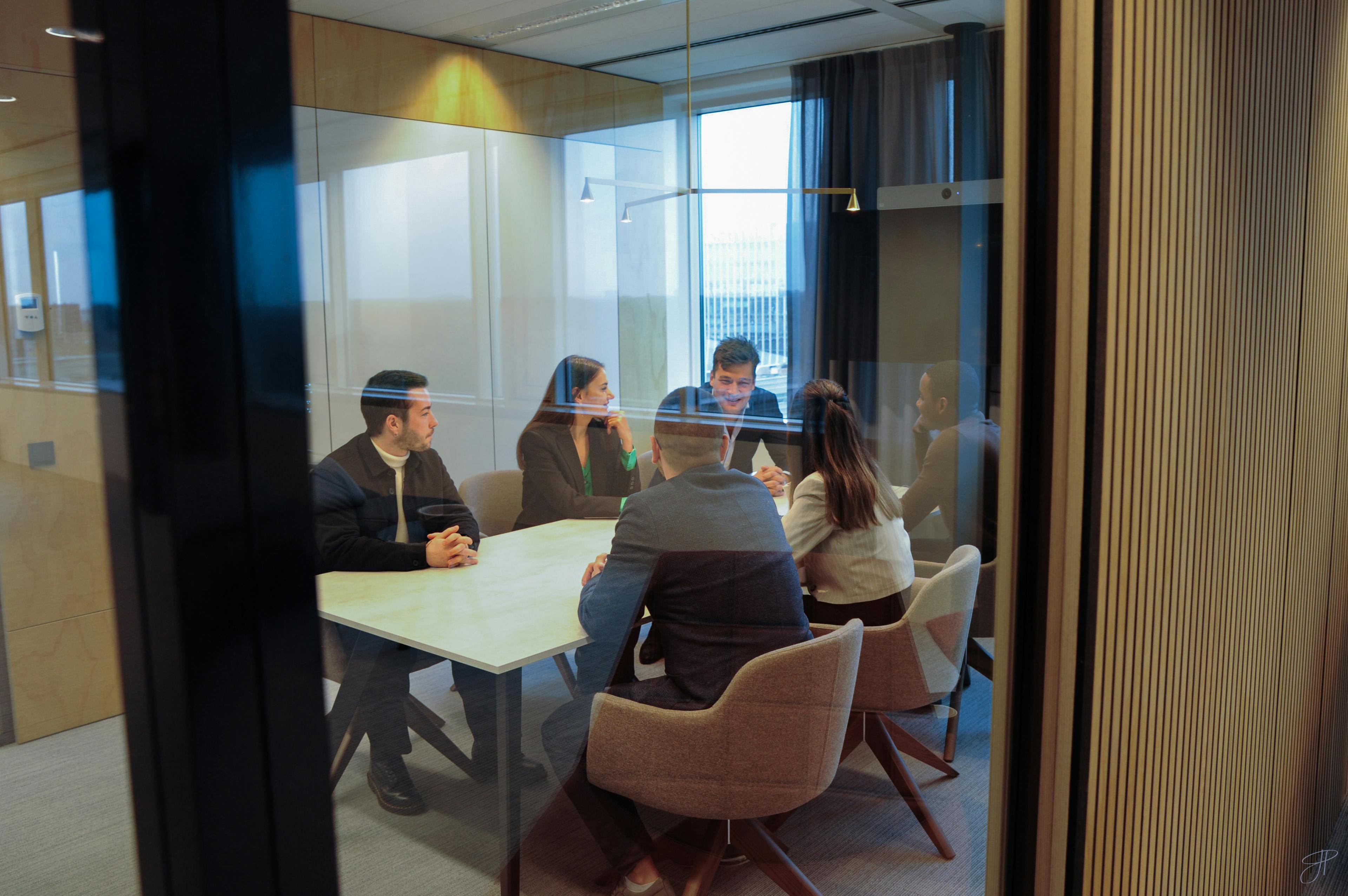 Five people sitting around a table in a conference room in Fusion Worldwide's EMEA office